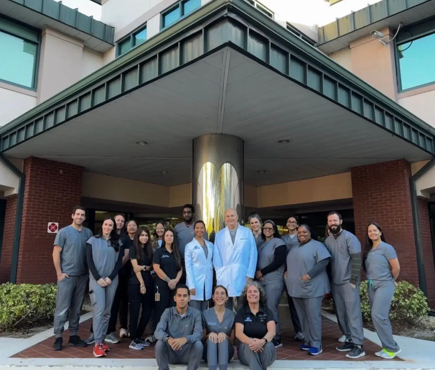 A group of smiling employees from the Orlando office posing together outdoors.